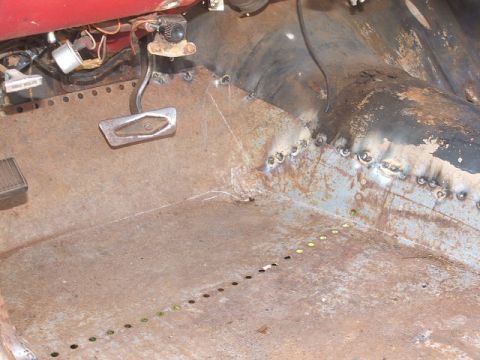 1966 Ford Ranchero - The interior floor pan of a vehicle shows extensive rust and repair work with visible welds.