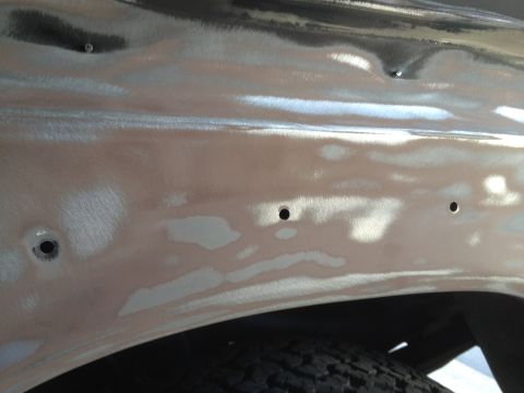 1979 Ford F-350 - Close-up of a vehicle's body panel undergoing repair, revealing bare metal and filler work.