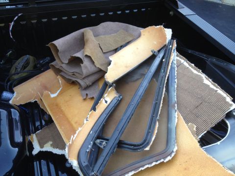 1979 Ford F-350 - Discarded interior trim and window frames are seen piled in the bed of a pickup truck.