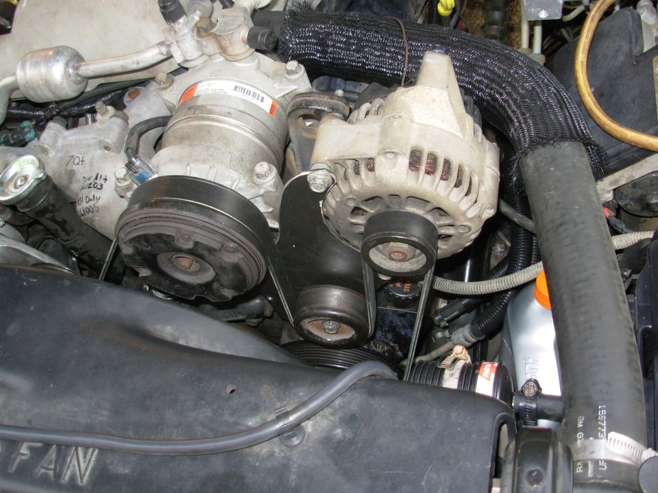 Close-up of alternator, A/C compressor, and serpentine belt in a GM truck engine bay