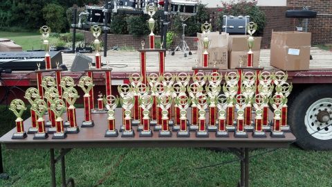 2007 Ford Mustang - A collection of trophies is displayed on a table, with musical instruments and a trailer in the background.
