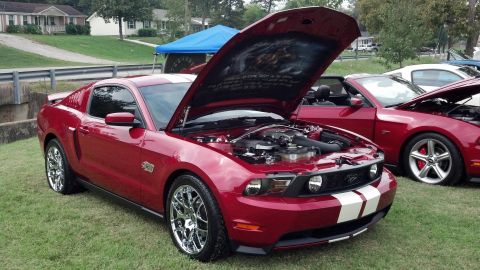 2007 Ford Mustang - A red 2007 Ford Mustang is displayed with its hood open, revealing the engine and custom artwork on the underside of the hood.