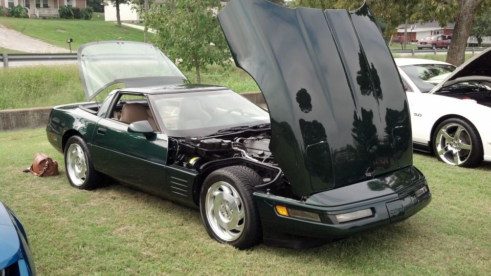 Green Chevrolet Corvette with hood and rear hatch open, showing engine and interior