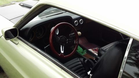 2007 Ford Mustang - The interior of a vintage car features a custom steering wheel and a manual shifter.