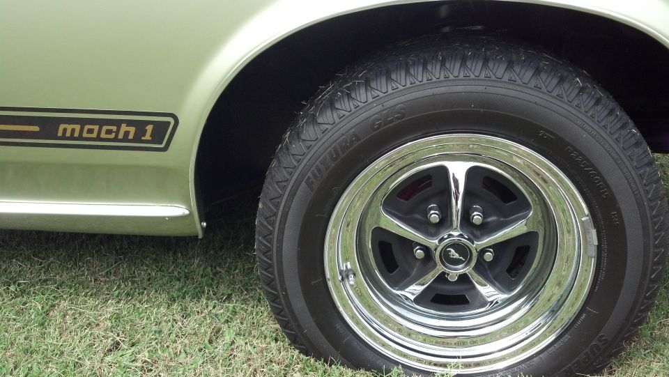 Mach 1 decal on a light green classic car side view with chrome wheel
