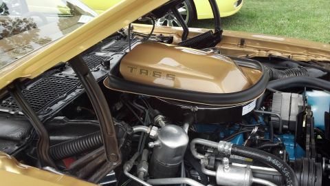 2007 Ford Mustang - Close-up of the engine compartment of a gold Pontiac Trans Am, showing the air cleaner assembly.