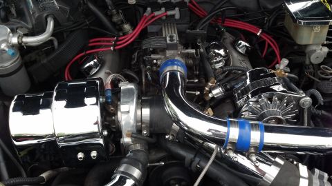 2007 Ford Mustang - A close-up view of a modified engine bay polished chrome components and vibrant red spark plug wires.