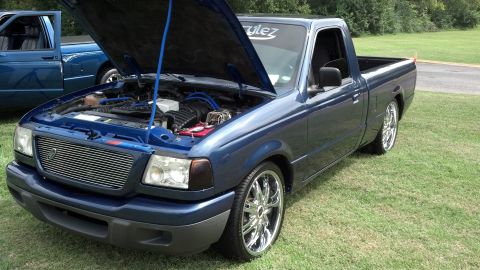 2007 Ford Mustang - A blue pickup truck is shown with its hood up, revealing the engine bay and custom modifications.