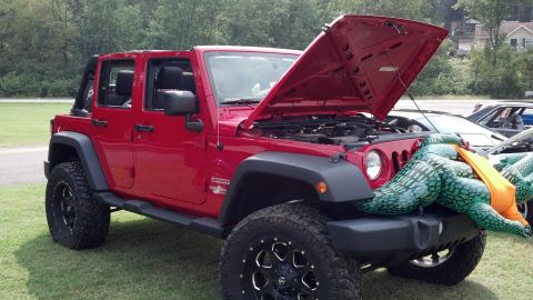 2007 Ford Mustang - Red Jeep Wrangler parked on grass with an inflatable alligator decoration on the front.