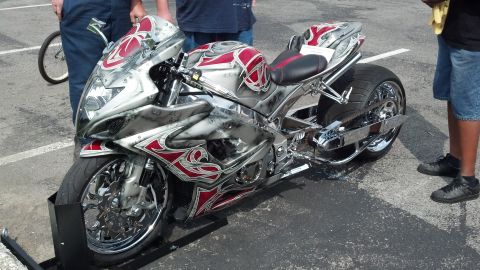2007 Ford Mustang - A custom motorcycle with intricate red and silver tribal graphics is displayed, a prominent chrome finish and a wide rear tire.
