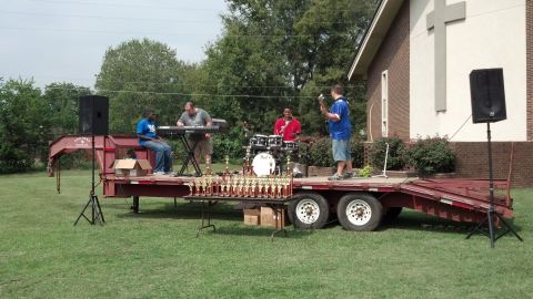 2007 Ford Mustang - A band performs on a trailer stage with trophies displayed, in front of a church building.