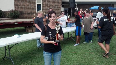 2007 Ford Mustang - A woman smiles while holding a trophy at an outdoor event with other people in the background.