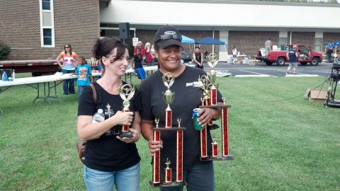 2007 Ford Mustang - Two women smile while holding trophies at an outdoor event.