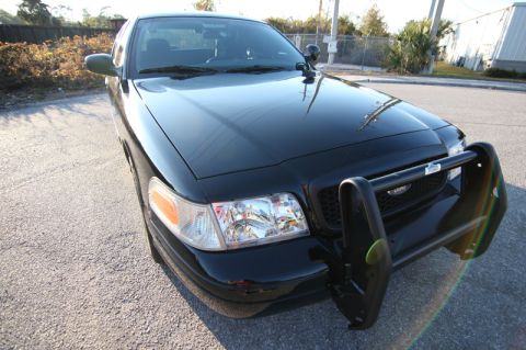 2004 Ford Crown Victoria - Black Ford Crown Victoria police car with push bumper is parked outside.