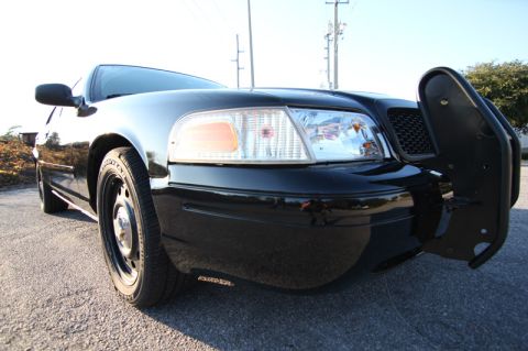 2004 Ford Crown Victoria - A black 2004 Ford Crown Victoria Police Interceptor is parked on a street, showing its front end and a push bumper.