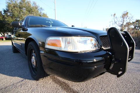 2004 Ford Crown Victoria - A black 2004 Ford Crown Victoria P71 police car is parked on a street, viewed from the front corner.