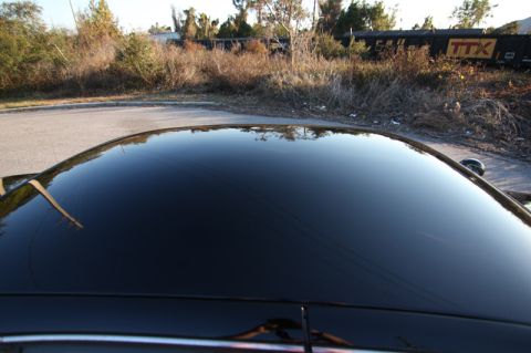 2004 Ford Crown Victoria - The glossy black roof of a car reflects the surrounding environment, including a train car marked with the TTX logo.
