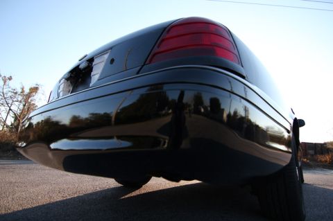 2004 Ford Crown Victoria - The rear of a black sedan is shown from a low angle against a clear sky.