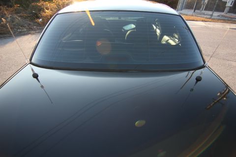 2004 Ford Crown Victoria - Rear view of a black 2004 Ford Crown Victoria sedan, showing its tinted rear window and dual antennas.