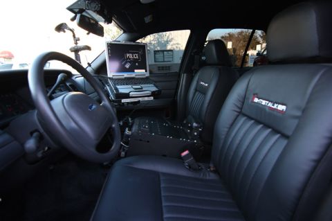 2004 Ford Crown Victoria - The interior of a police vehicle is shown, a laptop mounted on the dashboard and custom upholstery on the seats.