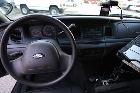 2004 Ford Crown Victoria - Interior view of a 2004 Ford Crown Victoria, showing the steering wheel, dashboard, and a mounted laptop.