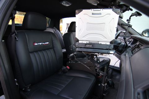 2004 Ford Crown Victoria - The interior of a police vehicle is shown, a laptop mounted on a stand and specialized seating.