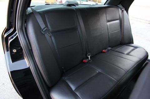 2004 Ford Crown Victoria - Interior view of the rear bench seat and seatbelts in a black vehicle.