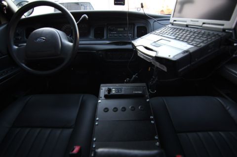 2004 Ford Crown Victoria - The interior of a police vehicle is equipped with a laptop and radio, suggesting its use in law enforcement.