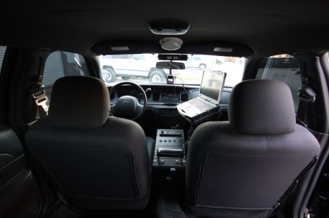 2004 Ford Crown Victoria - The interior of a police vehicle, likely a 2004 Ford Crown Victoria, is captured with a laptop mounted on the console.