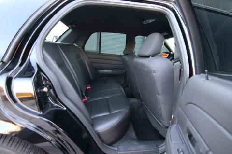 2004 Ford Crown Victoria - The interior of a black Ford Crown Victoria, showing the rear seats and door panel.