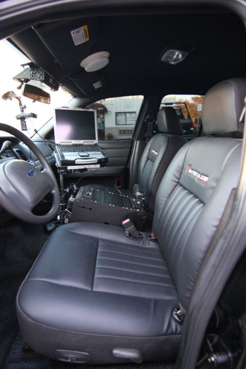 2004 Ford Crown Victoria - The interior of a police vehicle is equipped with a laptop and communication equipment between the front seats.
