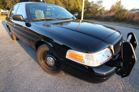 2004 Ford Crown Victoria - This black 2004 Ford Crown Victoria police car is shown from the front three-quarter view, equipped with a push bumper.