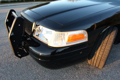 2004 Ford Crown Victoria - Front view of a black 2004 Ford Crown Victoria, equipped with a push bar and showing its front tire.