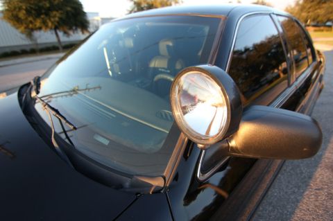 2004 Ford Crown Victoria - Front corner view of a black 2004 Ford Crown Victoria, equipped with a spotlight mounted on the driver's side mirror.