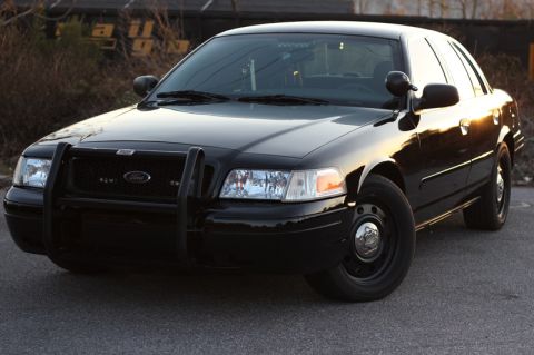 2004 Ford Crown Victoria - A black 2004 Ford Crown Victoria police interceptor is shown from a three-quarter front view.