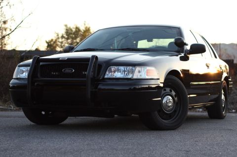 2004 Ford Crown Victoria - A black 2004 Ford Crown Victoria, equipped with a push bar, is shown in a front 3/4 view.