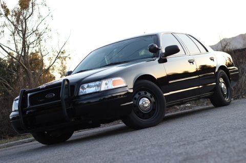 2004 Ford Crown Victoria - This black 2004 Ford Crown Victoria police car is shown from a 3/4 front angle, equipped with a push bar.