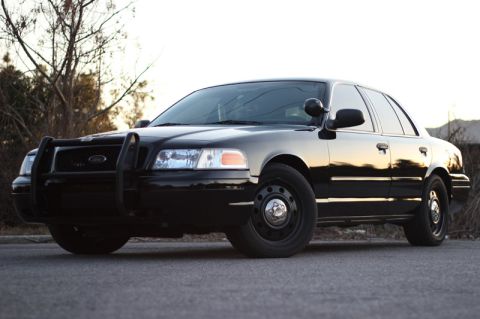 2004 Ford Crown Victoria - Black Ford Crown Victoria Police Interceptor with push bar is parked on a road.