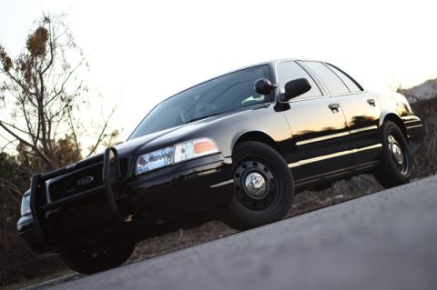 2004 Ford Crown Victoria - A black Ford Crown Victoria P71 police car is parked on an incline, with a push bumper on the front.