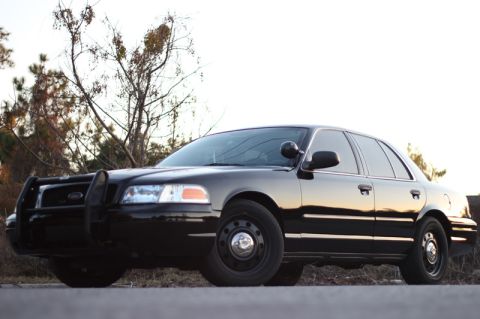 2004 Ford Crown Victoria - Black Ford Crown Victoria Police Interceptor with push bar is parked outside.