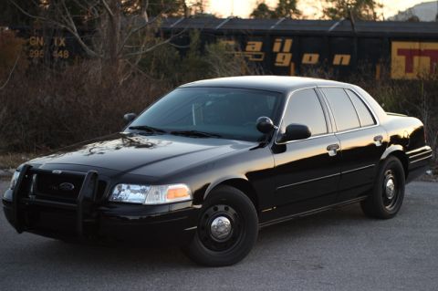 2004 Ford Crown Victoria - A black Ford Crown Victoria Police Interceptor is parked with a train car in the background.