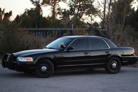 2004 Ford Crown Victoria - Side view of a black 2004 Ford Crown Victoria sedan with tinted windows and a push bar.