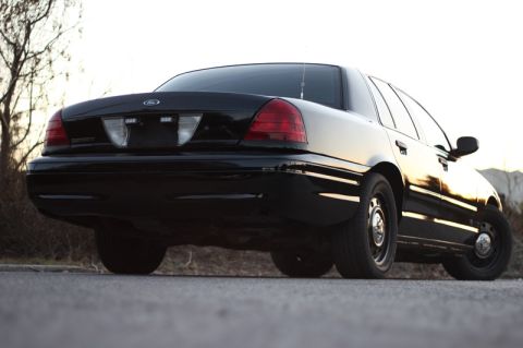 2004 Ford Crown Victoria - Rear view of a black 2004 Ford Crown Victoria, showing its distinctive taillights and body style.