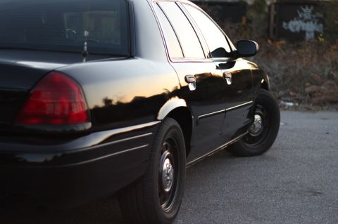 2004 Ford Crown Victoria - A black 2004 Ford Crown Victoria is parked on asphalt with graffiti in the background.