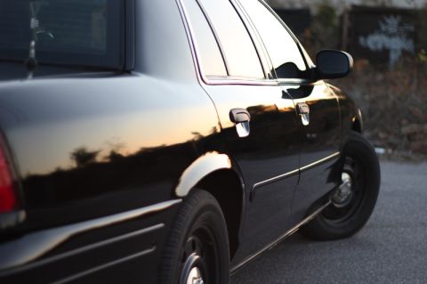 2004 Ford Crown Victoria - Side profile of a black 2004 Ford Crown Victoria with reflections of the sky on its body.