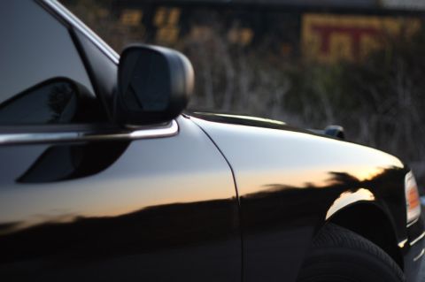2004 Ford Crown Victoria - The reflection of the sunset is visible on the polished black paint of the vehicle.