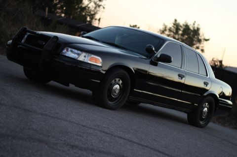 2004 Ford Crown Victoria - A black 2004 Ford Crown Victoria sedan is shown from a three-quarter front angle, equipped with a push bar.