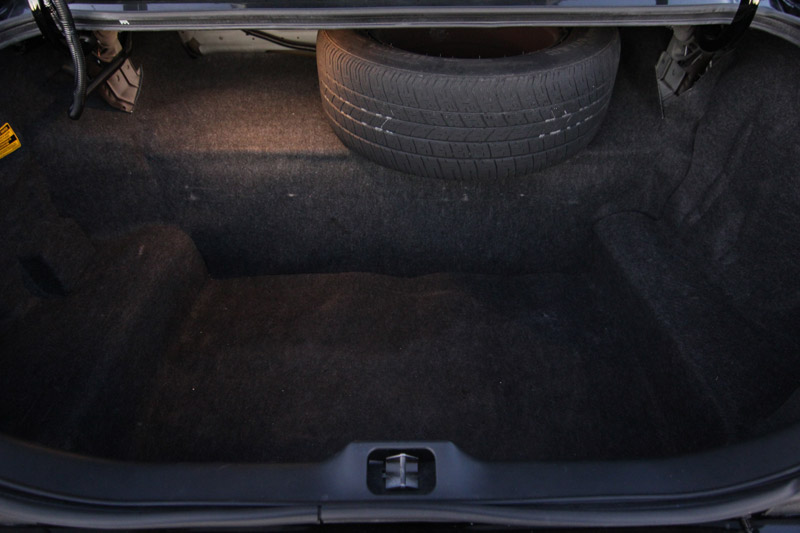 Car trunk interior showing carpet lining and a spare tire mounted in the well