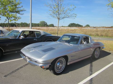 1991 Ford LTD Crown Victoria - A classic silver Chevrolet Corvette Sting Ray is parked in a lot on a sunny day.