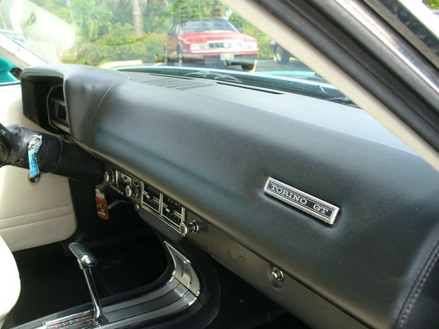 1970 Ford Torino GT interior showing dashboard, shifter, and red car in background